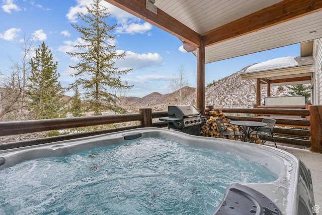 snow covered pool featuring a mountain view, a hot tub, and a grill