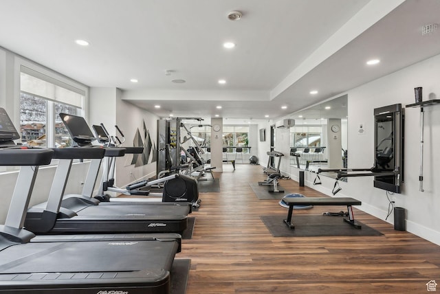 exercise room with hardwood / wood-style flooring and a wall unit AC