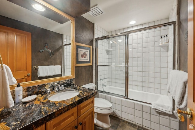 full bathroom featuring vanity, combined bath / shower with glass door, and toilet