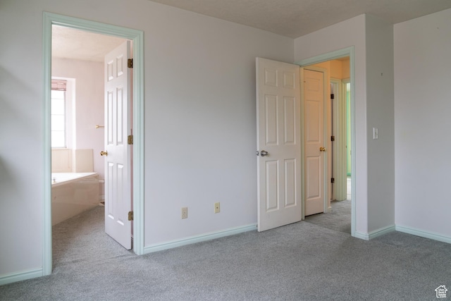 unfurnished bedroom featuring ensuite bathroom and light carpet