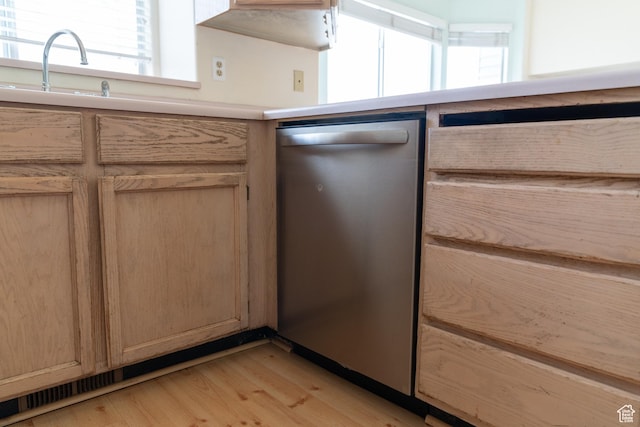 kitchen with stainless steel dishwasher, light brown cabinetry, sink, and light hardwood / wood-style flooring