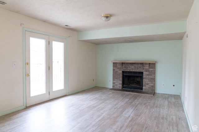 unfurnished living room featuring a fireplace, light hardwood / wood-style flooring, and a textured ceiling