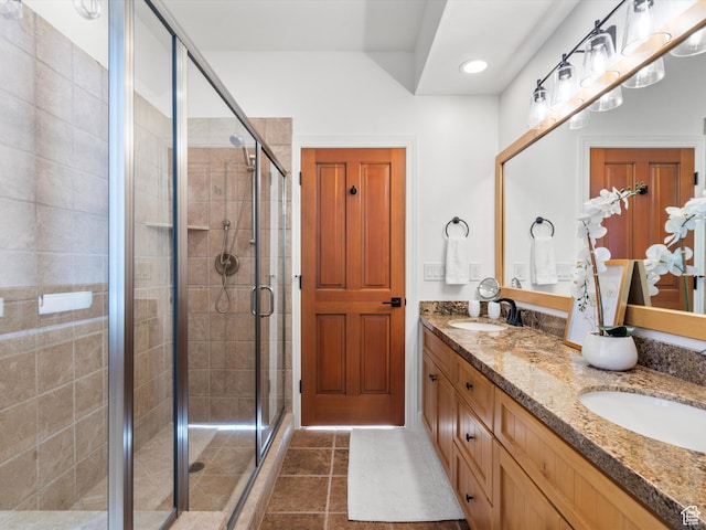 full bathroom with double vanity, tile patterned flooring, a stall shower, and a sink