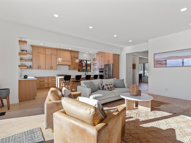 living area with light wood-type flooring, recessed lighting, and baseboards