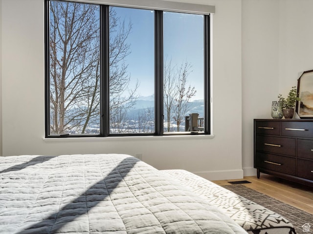 bedroom with baseboards, light wood-style floors, and multiple windows