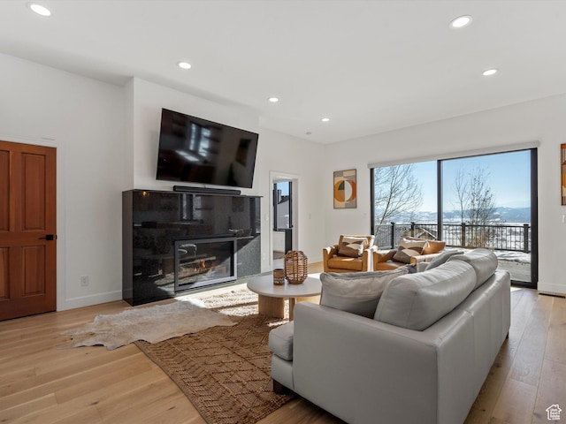 living room with recessed lighting, light wood finished floors, a tiled fireplace, and baseboards