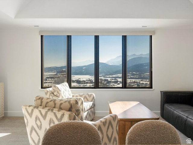 living area featuring baseboards, a wealth of natural light, a mountain view, and carpet