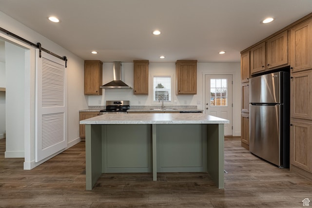 442 W Pipe Springs Dr, Kanab, UT 84741 - kitchen featuring wall chimney range hood, hardwood / wood-style flooring, stainless steel appliances, a kitchen island, and a barn door