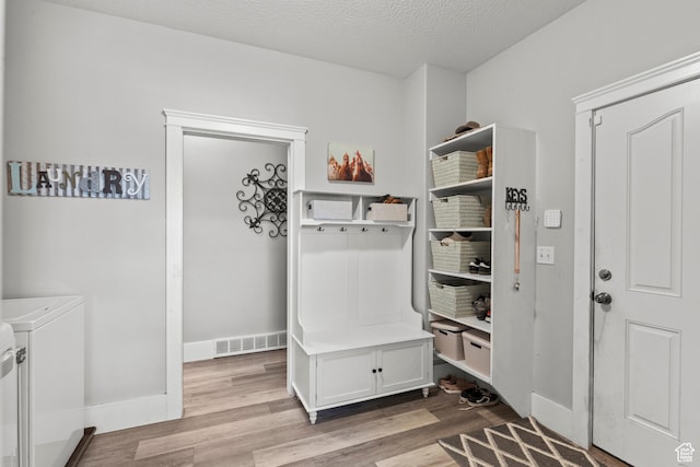 mudroom featuring washer and clothes dryer, wood finished floors, a textured ceiling, visible vents, and baseboards