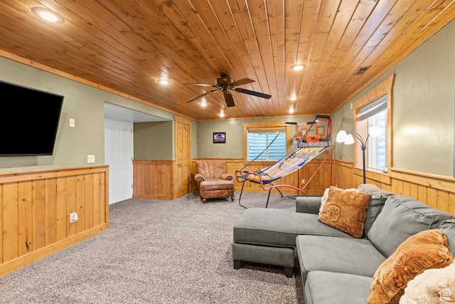 carpeted living room featuring plenty of natural light, ceiling fan, wood ceiling, wood walls, and a wainscoted wall