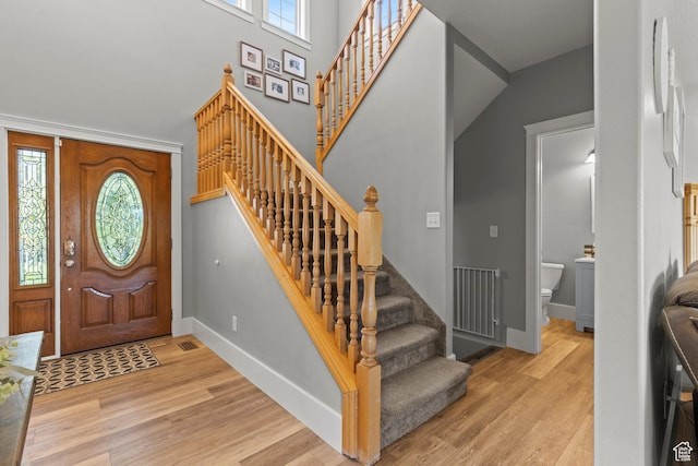 entryway featuring baseboards, stairs, a high ceiling, and wood finished floors