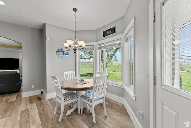 dining space with baseboards, a notable chandelier, and light wood-style floors