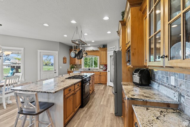 kitchen featuring plenty of natural light, brown cabinetry, a sink, stainless steel appliances, and light wood-type flooring