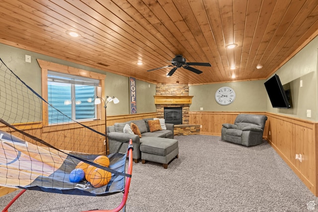 carpeted living room with a fireplace, wood ceiling, and a wainscoted wall