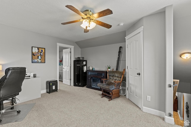 carpeted office space featuring baseboards, a ceiling fan, and a glass covered fireplace