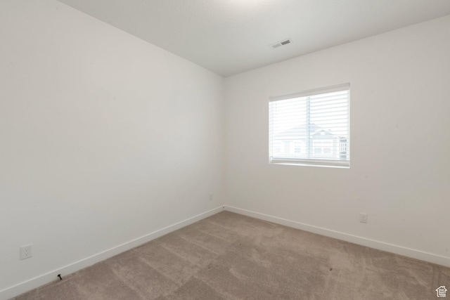 empty room featuring light colored carpet, visible vents, and baseboards
