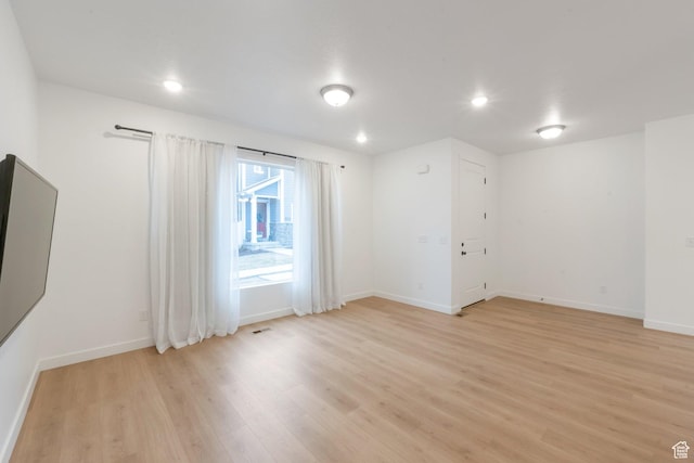 empty room with baseboards, recessed lighting, and light wood finished floors