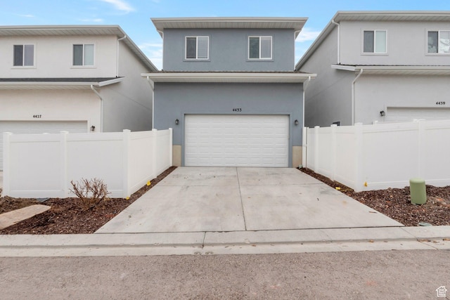 view of front of house with fence, stucco siding, driveway, and an attached garage