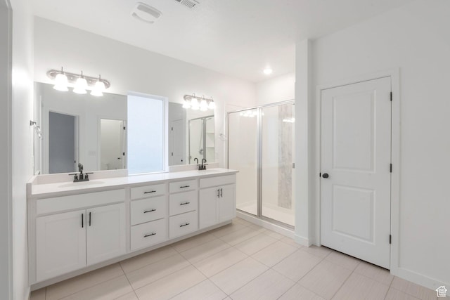 full bath featuring a stall shower, double vanity, a sink, and tile patterned floors