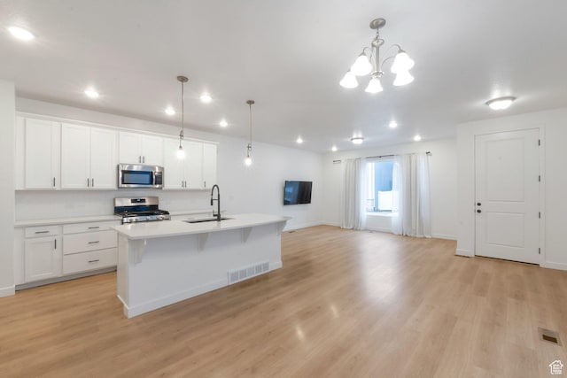 kitchen featuring a sink, stainless steel appliances, light wood-type flooring, visible vents, and light countertops