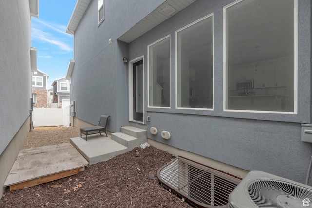 view of home's exterior featuring entry steps, a patio, stucco siding, central air condition unit, and fence