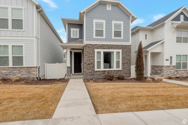 craftsman-style home with a front lawn, stone siding, and board and batten siding
