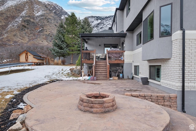 1533 Rosanna Ln, Alpine, UT 84004 - snow covered patio featuring an outdoor fire pit, a deck with mountain view, and a trampoline