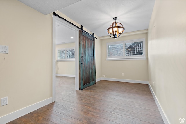 1533 Rosanna Ln, Alpine, UT 84004 - empty room featuring a notable chandelier, hardwood / wood-style flooring, a barn door, and a textured ceiling