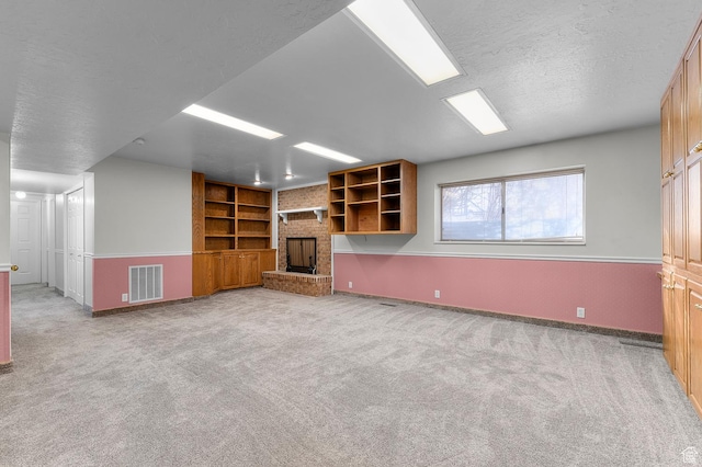 unfurnished living room featuring visible vents, light colored carpet, a brick fireplace, and a textured ceiling