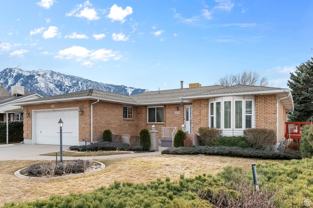 single story home featuring a chimney, brick siding, an attached garage, and driveway