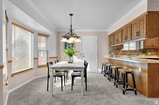 dining room with plenty of natural light, light colored carpet, crown molding, and baseboards