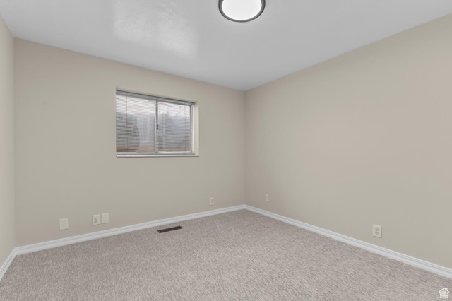 carpeted spare room featuring baseboards and visible vents