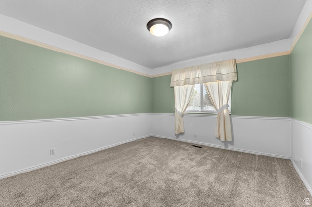 carpeted spare room featuring visible vents and a textured ceiling