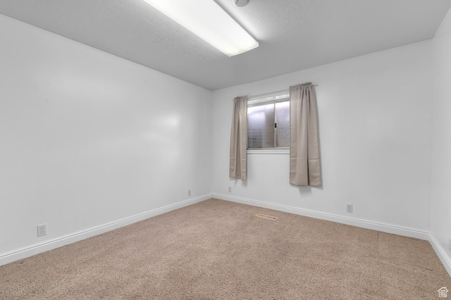 carpeted empty room featuring visible vents and baseboards