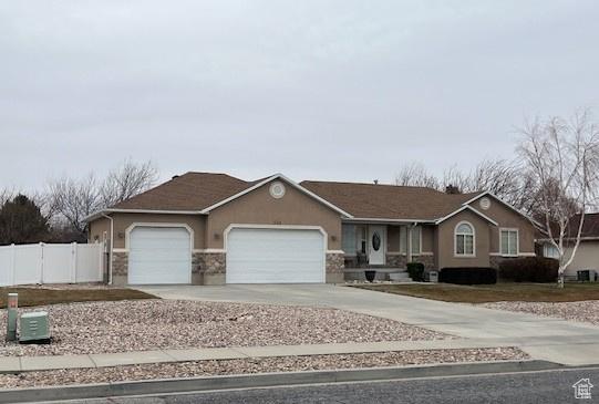 334 S Lariat Way, Grantsville, UT 84029 - ranch-style house with stucco siding, an attached garage, driveway, and fence