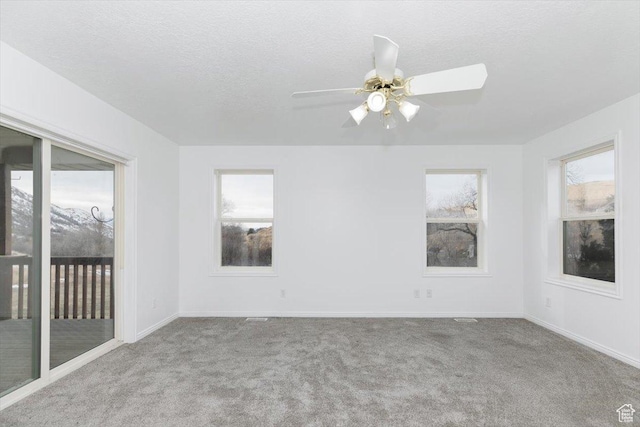 spare room with ceiling fan, light colored carpet, and a textured ceiling