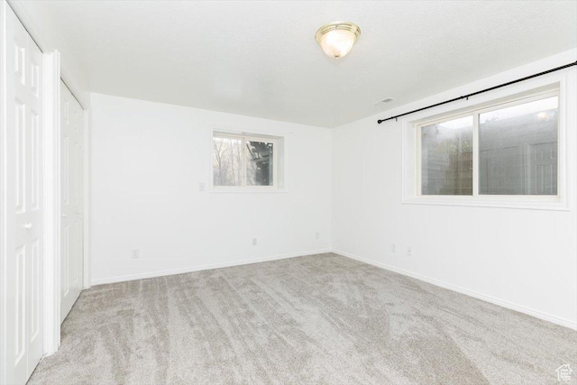 spare room featuring light colored carpet and a textured ceiling