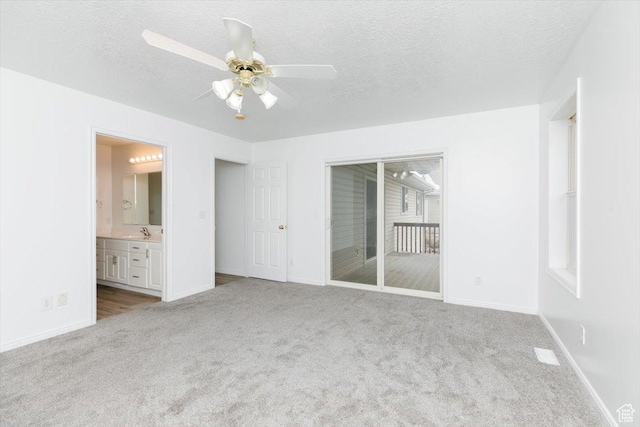 unfurnished bedroom with ceiling fan, light colored carpet, sink, and a textured ceiling
