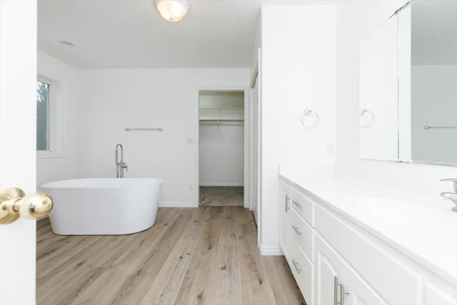 bathroom featuring hardwood / wood-style floors, vanity, and a washtub