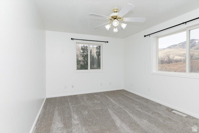 carpeted spare room featuring ceiling fan and a mountain view