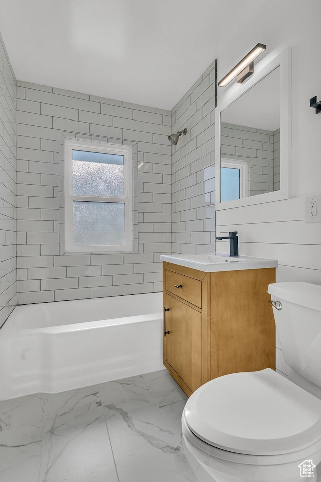 full bathroom featuring vanity, tiled shower / bath, tile walls, and toilet