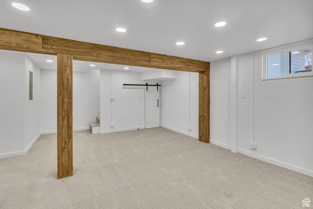 basement with a barn door and light carpet
