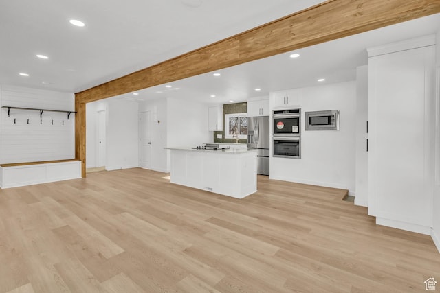 unfurnished living room with beamed ceiling and light hardwood / wood-style flooring