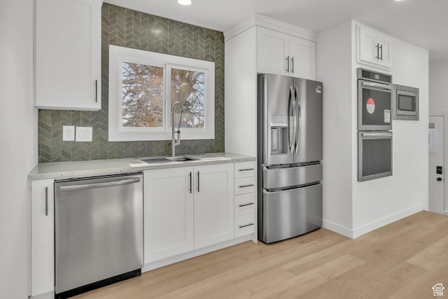 kitchen with sink, stainless steel appliances, light stone countertops, light hardwood / wood-style floors, and white cabinets