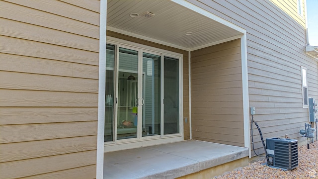 view of exterior entry with a patio and cooling unit