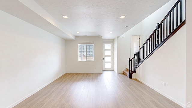 entryway with a textured ceiling and light hardwood / wood-style floors