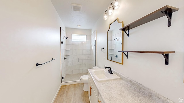 bathroom with hardwood / wood-style flooring, vanity, a textured ceiling, a shower with shower door, and toilet