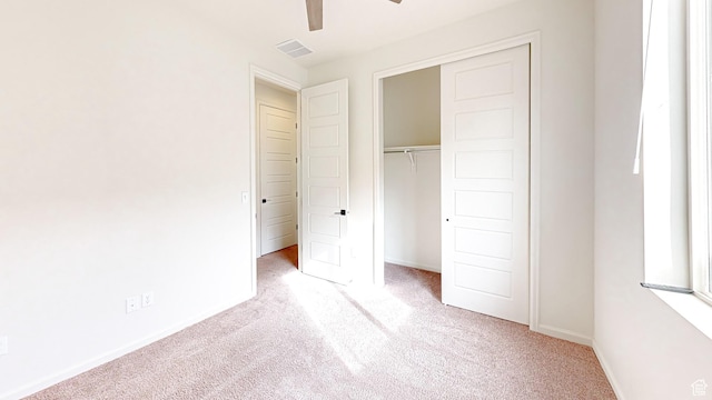 unfurnished bedroom featuring light carpet, a closet, and ceiling fan
