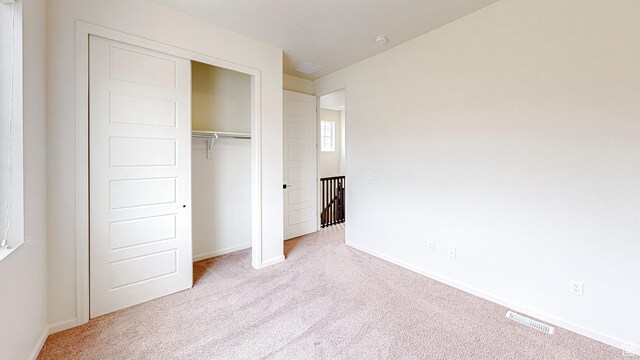 unfurnished bedroom featuring light colored carpet and a closet