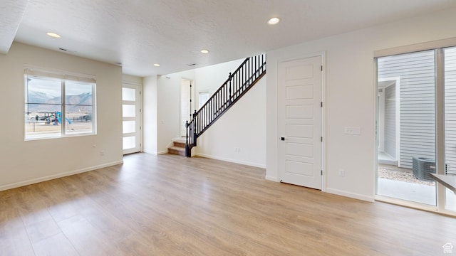 unfurnished living room with a textured ceiling and light wood-type flooring